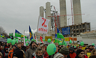 Demonstrationsteilnehmer vor der Baustelle des Kohlekraftwerks Neurath mit grünen Luftballons und Transparenten